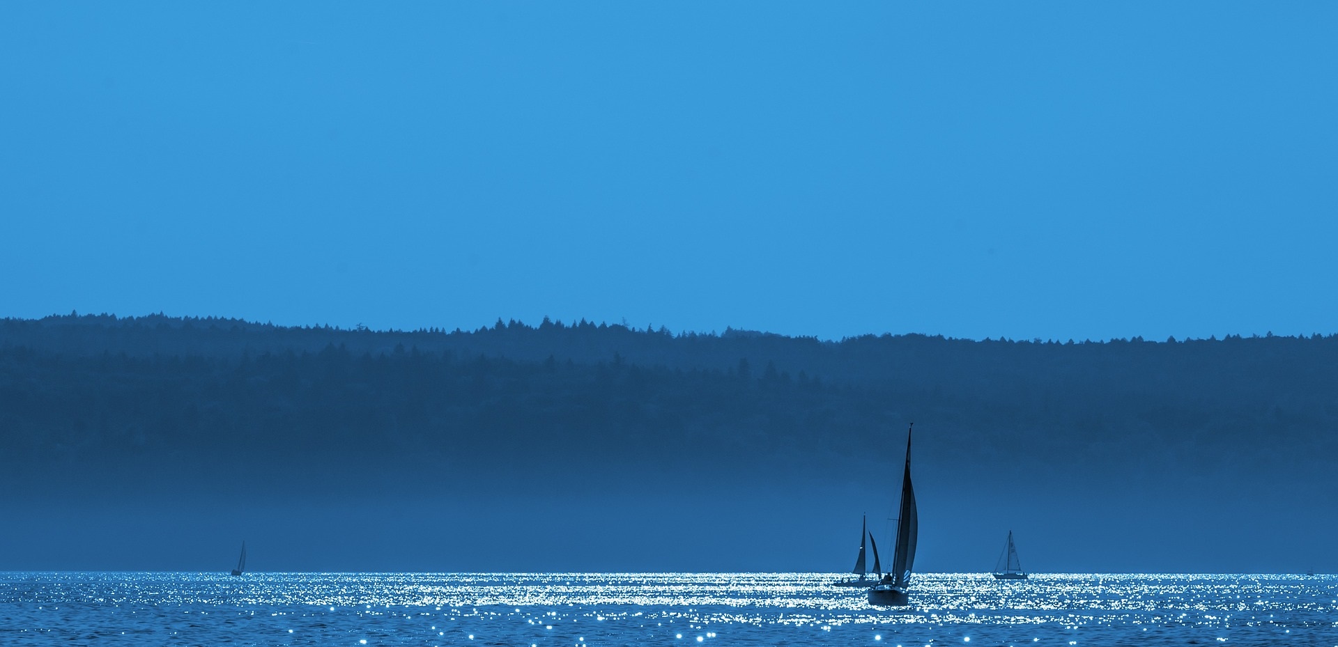 Blå bakgrundsbild, hav med segelbåtar.