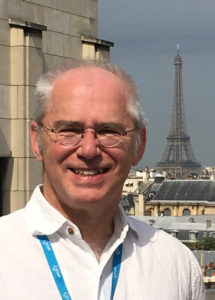 Lars Lundberg i profilbild iförd vi skjorta och glasögon. I bakgrunden syns Eiffeltornet.